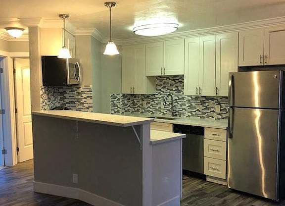 A kitchen with a white island and a stainless steel refrigerator.