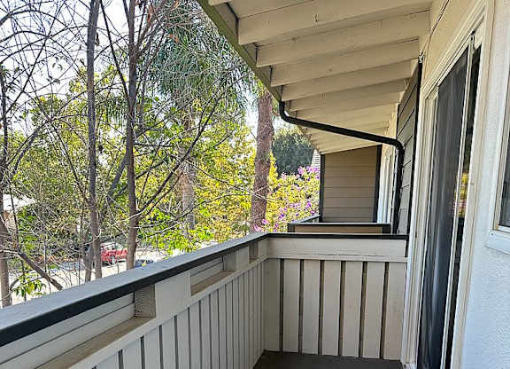 A balcony with a white railing and a black floor.
