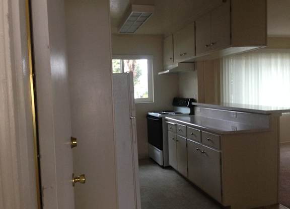 A kitchen with a white door and a window.