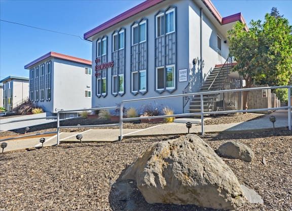 a building with stairs and a rock in front of it