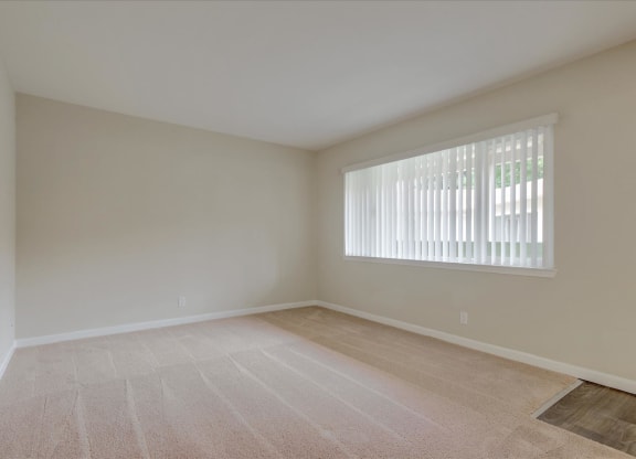 an empty living room with a large window and tiled floors