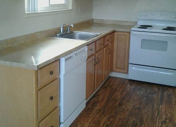 A kitchen with wooden cabinets and a white stove.