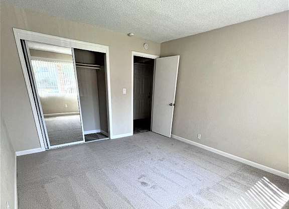 A room with a carpeted floor and two doors.