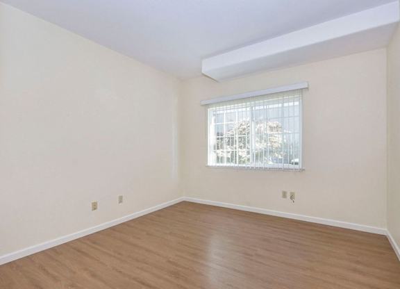 Empty room with a window and wooden floor.