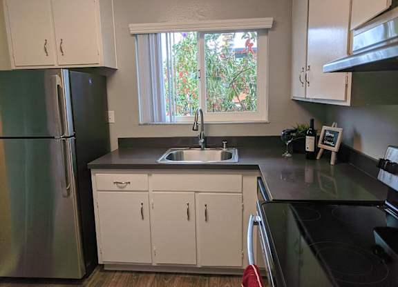 A kitchen with white cabinets and a black countertop.