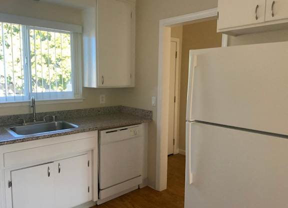 A kitchen with white cabinets and a white refrigerator.
