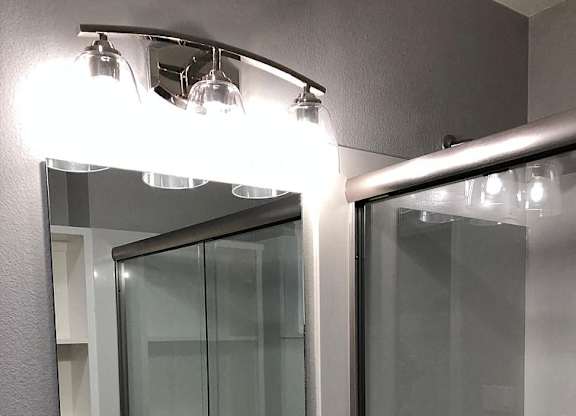 A bathroom with a sink, mirror, and shower.