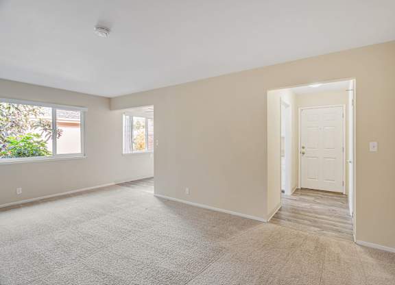 A room with a carpeted floor and a door leading to another room.