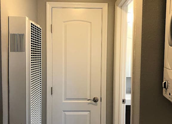 A white door is in a hallway with a washer and dryer on the side.