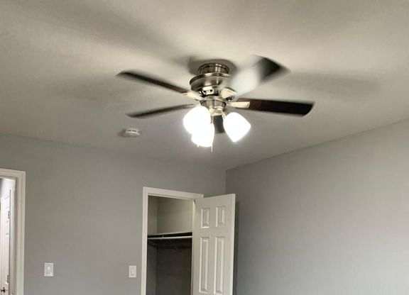 A room with a ceiling fan and carpeted floor.