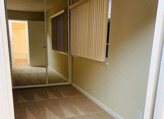 a hallway with a carpeted floor and a mirrored closet