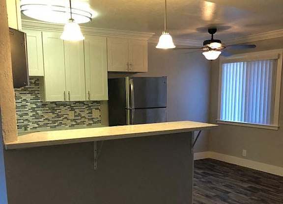 A kitchen with a refrigerator, cabinets, and a countertop.