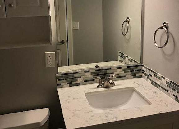 A bathroom with a marble counter top and a white sink.