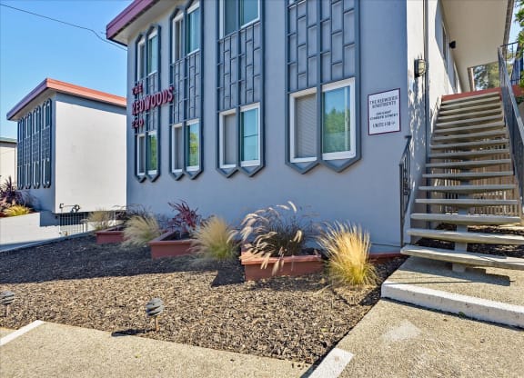 the front of a building with stairs and plants in front of it