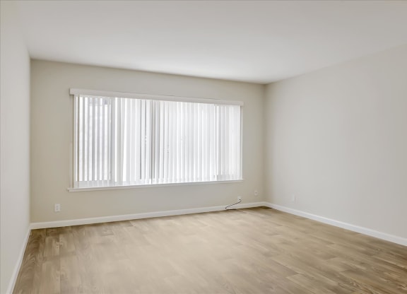 an empty room with a window and wood floors