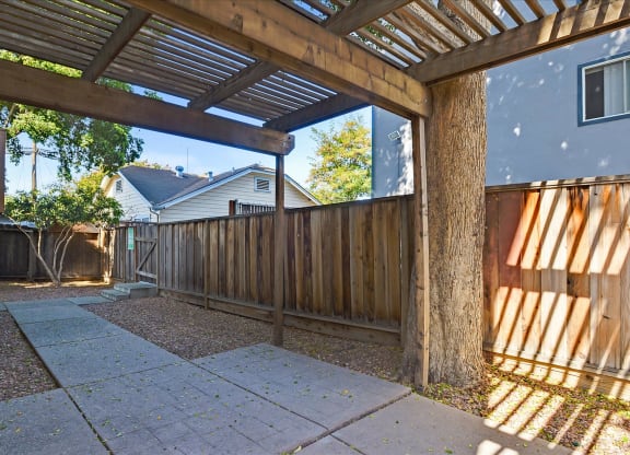 A wooden pergola with a roof and a concrete floor.