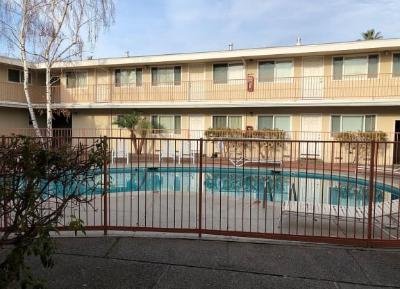 a swimming pool is behind a wrought iron fence