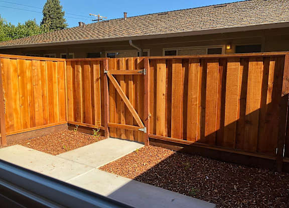 A wooden fence with a gate is in front of a house.