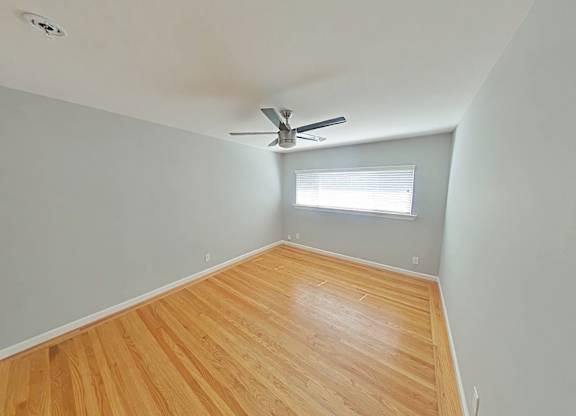 A room with a ceiling fan and wooden flooring.