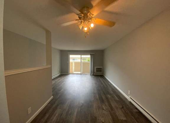 A room with a ceiling fan and wooden flooring.