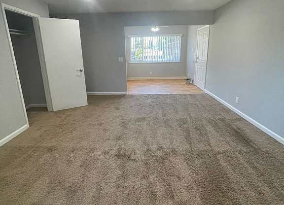 an empty living room with a carpeted floor and a window