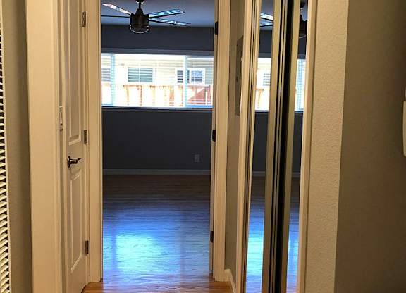 A hallway with a ceiling fan and sliding glass doors.