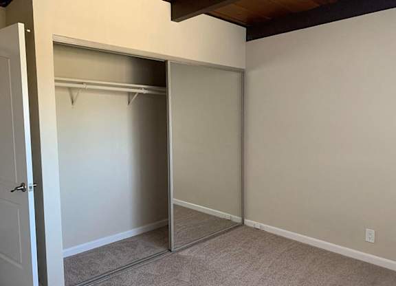 a bedroom with a closet with a mirrored door