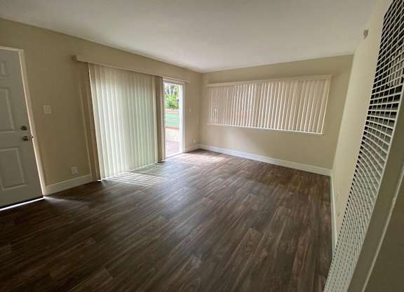 an empty living room with wood floors and a sliding glass door
