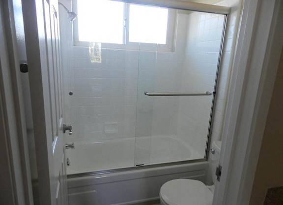 A white toilet is in a bathroom with a glass shower door.