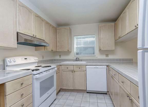 A kitchen with white appliances and wooden cabinets.