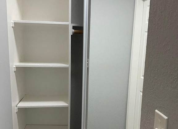A white shelving unit with four shelves is open to the left.