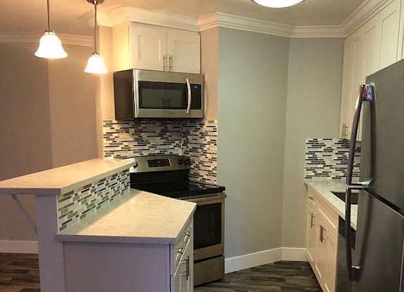 A kitchen with a white counter top and a black refrigerator.