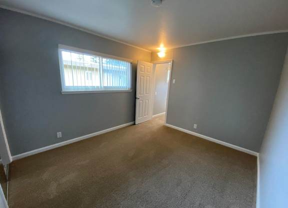 A room with a carpeted floor and a door leading to another room.
