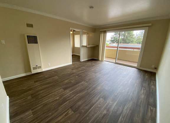 A room with wooden flooring and a sliding glass door.
