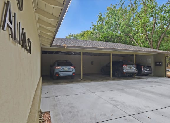 A carport with three cars parked in it.