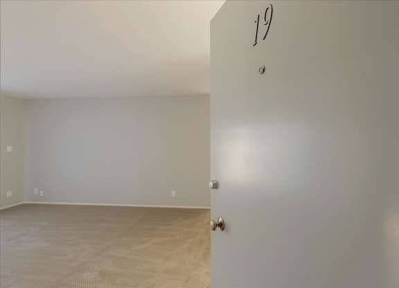 an empty living room with a white wall and a door