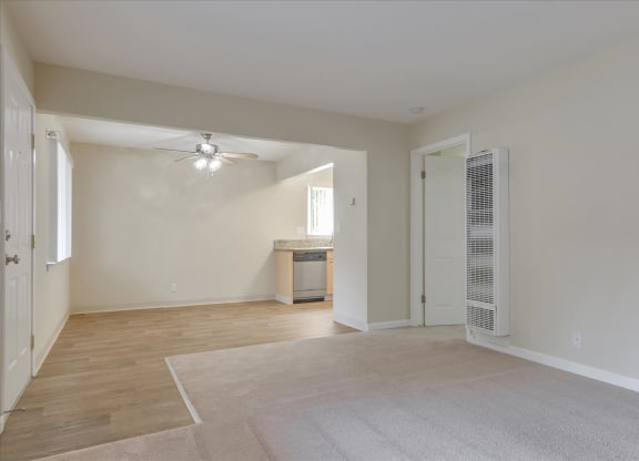 an empty living room with a ceiling fan and a door to a bathroom