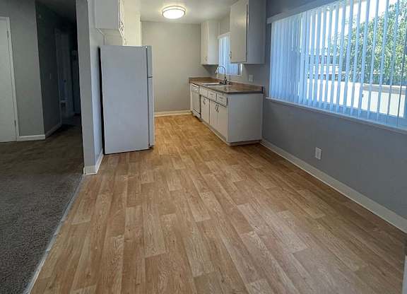 an empty living room and kitchen with a ceiling fan
