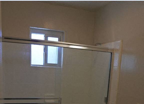 A white toilet sits in a bathroom next to a walk-in shower.