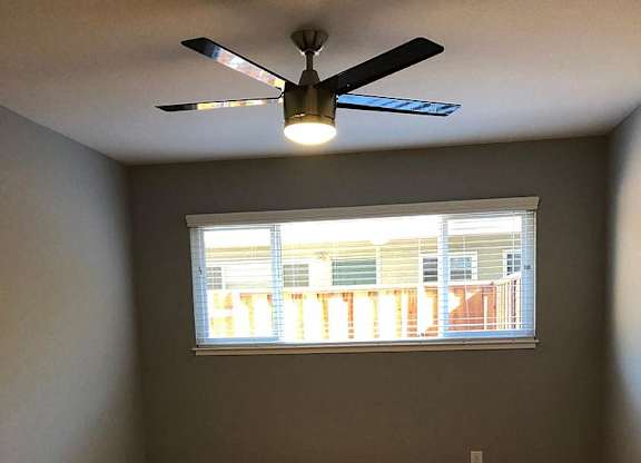 A room with a ceiling fan and a window.