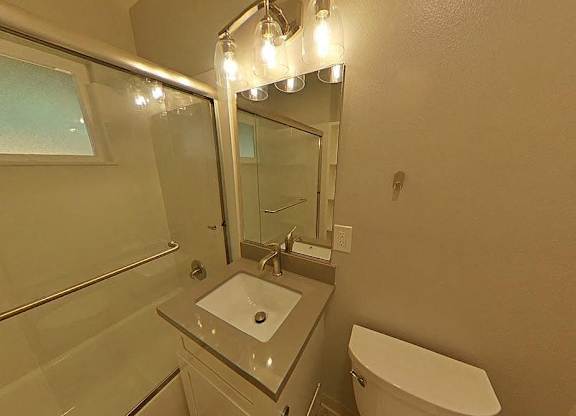 A bathroom with a sink, toilet, and mirror.