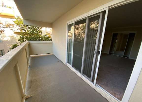 A balcony with a glass door leading to a room.
