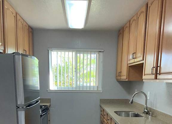 A kitchen with wooden cabinets and a stainless steel refrigerator.