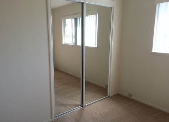 A room with a carpeted floor and a large mirror.