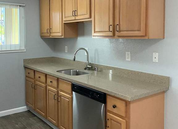 A kitchen with wooden cabinets and a stainless steel dishwasher.
