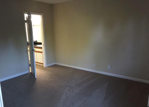 A room with a carpeted floor and a doorway leading to another room.