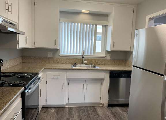 A kitchen with white cabinets and a stainless steel refrigerator.