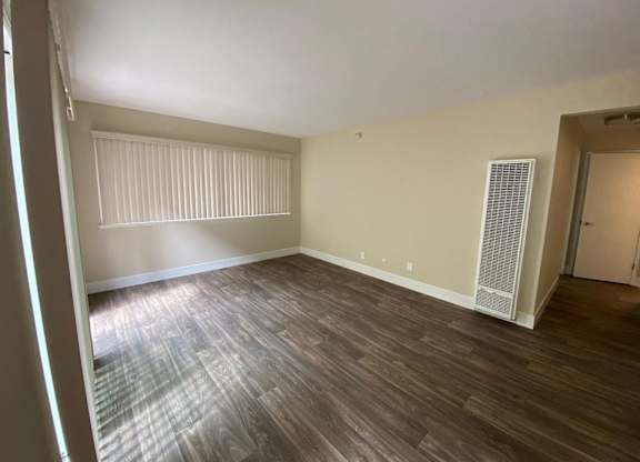an empty living room with wood flooring and a window