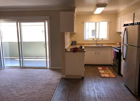 A kitchen with a refrigerator, sink, and cabinets.