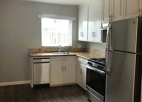 A kitchen with a refrigerator, stove, and sink.
